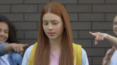 Zalim gençler zencefilli kıza işaret ediyor, kızıl saçlıyla dalga geçiyor, okul zorbalığı