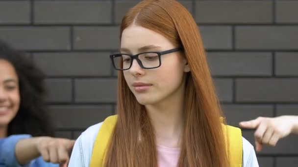 Gemiddelde schoolkinderen wijzende vingers bij Smart Girl, plagen over brillen — Stockvideo