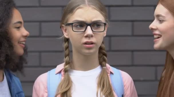 Ängstliches Teenager-Mädchen, das Ohren vor Mobbing verdeckt, Klassenkameraden, die Namen nennen, Hänseleien — Stockvideo