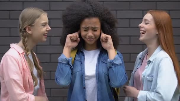 Biracial tiener meisje bedekt oren van pesten, spot van klasgenoten, racisme — Stockvideo