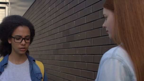 Niña de la escuela detener biracial estudiante femenina en el patio de la escuela, la intimidación racial — Vídeo de stock