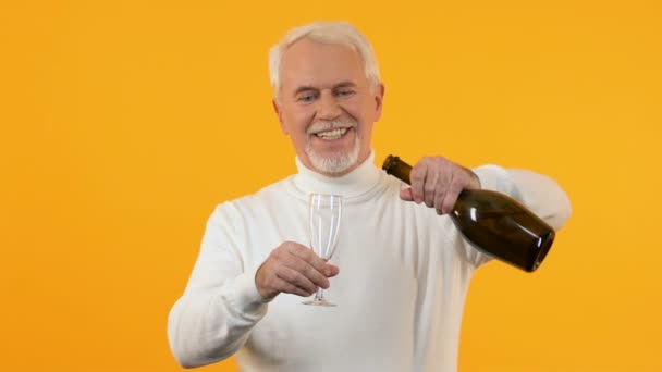 Heureux homme âgé versant verre de champagne sous confettis tombant, célébration — Video