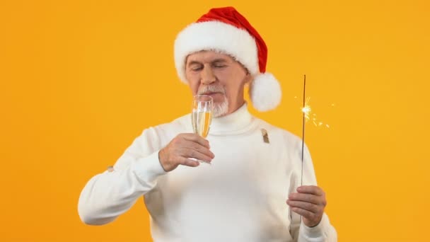 Celebrare uomo maturo cappello di Babbo Natale bere champagne da vetro che tiene sparkler — Video Stock