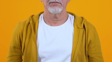 Gri sakallı adam sessizlik jesti gösteren, gizli bilgilerin ifşa edilmemesi