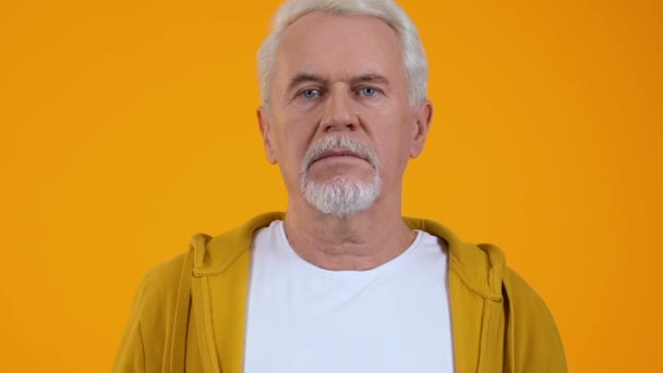 オレンジ色の背景に驚いた引退した男、衝撃的なニュース、予期せぬ問題 — ストック動画