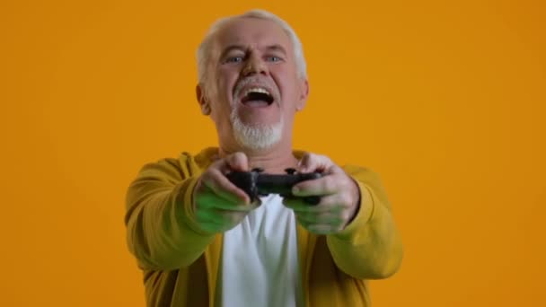 Захоплений чоловік на пенсії грає у відеоігри джойстиком, сучасними технологіями, хобі — стокове відео