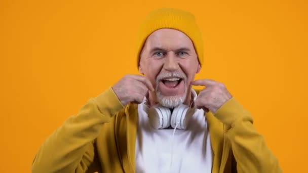 Positieve oude man in stijlvolle doek en koptelefoon dansen, jong voelen, vrije tijd — Stockvideo