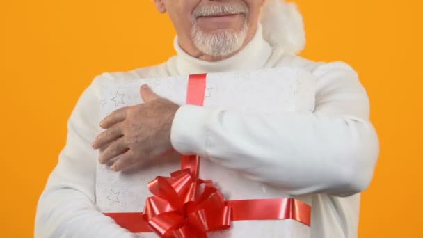 Gioiosa barba grigia maschio contenente una scatola regalo con nastro rosso, felicità regalo — Video Stock
