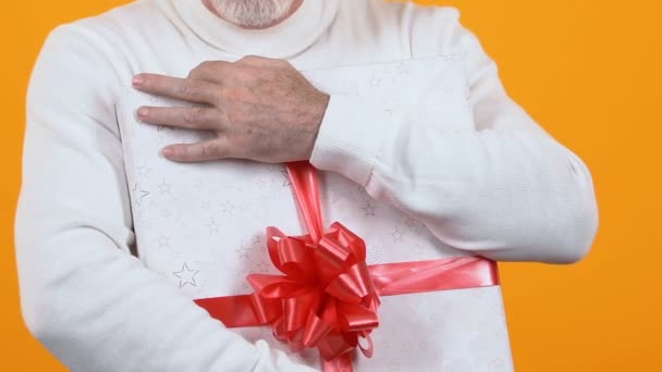 Vieil homme gourmand tenant une boîte cadeau enveloppée, pensionné capricieux, souvenir — Video