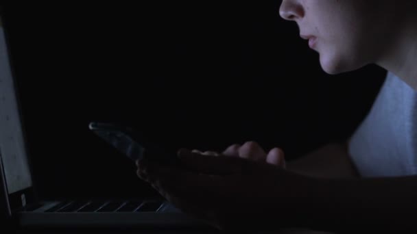 Девушка регистрируется на ноутбуке, использует телефон для двухфакторной аутентификации, крупным планом — стоковое видео
