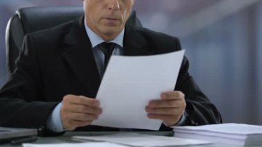 Belgeler üzerinde çalışan kıdemli erkek Müdür, Sözleşme ayrıntılarını okuma, politikacı