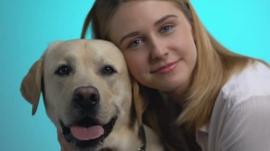 Mavi arka planda güzel genç kadın ve Labrador köpek görünümlü kamera çekim