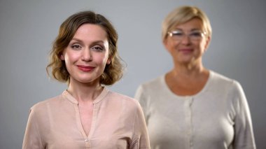 Güzel kadın kamera gülümsüyor, Yaşlı Bayan arkasında, güvenli ve sağlıklı yaşlanma