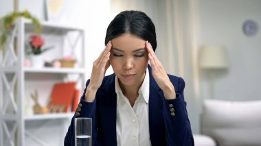 Stresli çalışan baş ağrısı muzdarip, masada su bardağı, sağlık