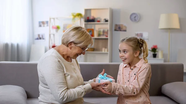 Granddaughter Giving Gift Box Grandmother Hugging Holiday Surprise — Stock Photo, Image