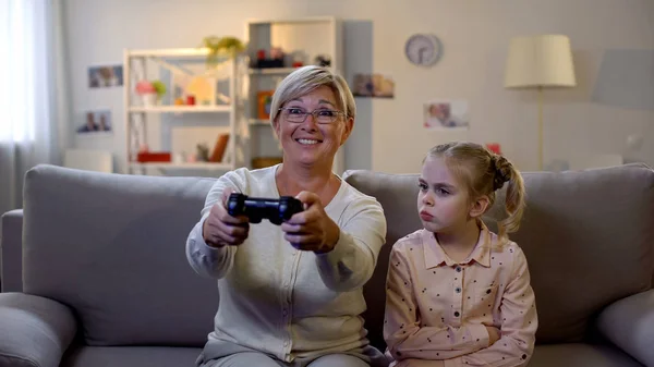 Eccitata Nonna Giocare Video Gioco Ignorando Triste Nipote Seduto Divano — Foto Stock