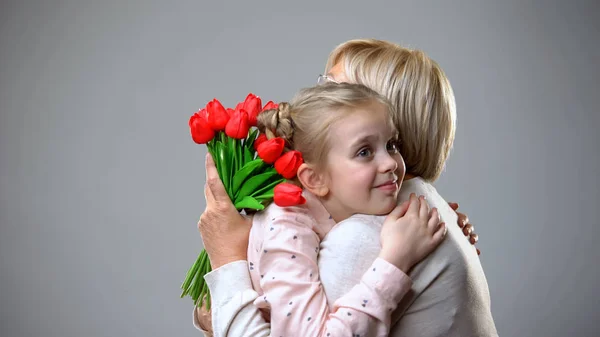 Positives Mädchen Umarmt Großmutter Hält Blumenstrauß Gratuliert — Stockfoto