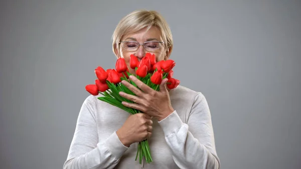 Sênior Feminino Cheirar Flores Sorrindo Câmera Presente Romântico Feminilidade — Fotografia de Stock