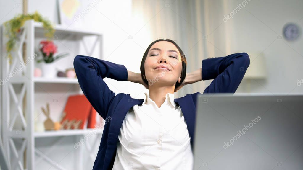 Satisfied business lady relaxing on chair front laptop, finished project, rest