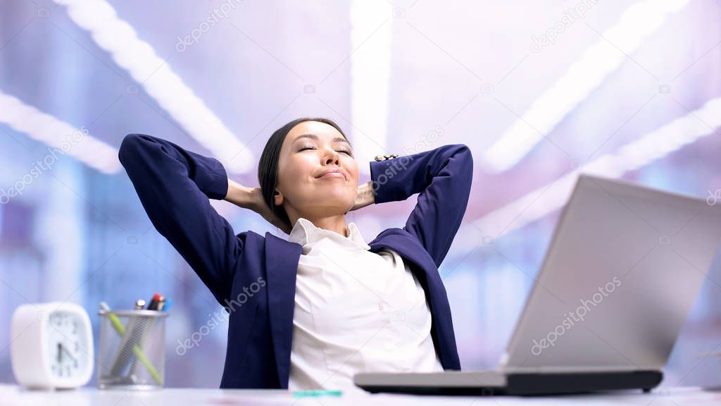 Glad business lady relaxing on chair front of laptop in office, work break