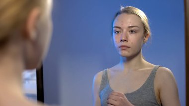 Ayna önünde güvensizlik acı önünde duran yüzünde akne lekeleri ile Kız