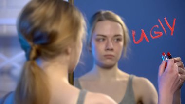 Üzgün üniversite öğrencisi ayna, zorbalık sorunu ruj ile kelime çirkin yazma