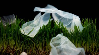 Plastic bags and cups lying on grass, trash left after irresponsible picnickers clipart