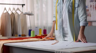 Kadın tasarımcı masadaki kağıt desenine bakıyor, gelecekteki tasarımı hayal ediyor