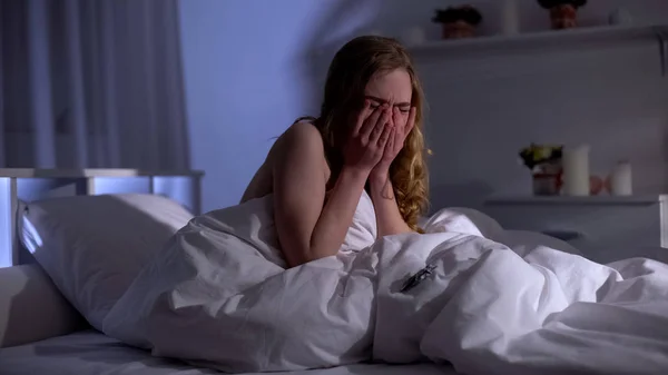 Absolutely desperate woman crying in bed, crumpled dollar, sexual slavery