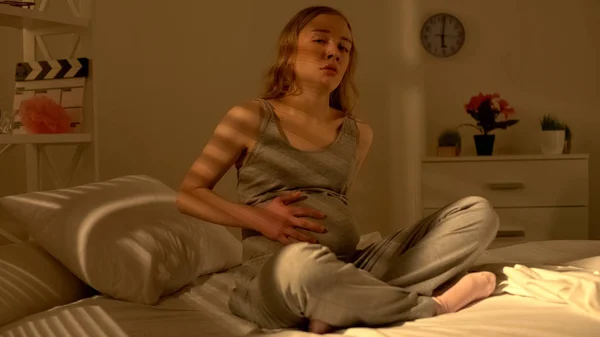 ベッドの上に座って腹に痛みを感じるうつ病の妊娠中の女性 健康上の問題 — ストック写真