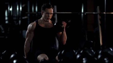 Yaz için eğitim alternanslı pazı kıvırmak, yakışıklı vücut geliştirmeci yapıyor oturmuş