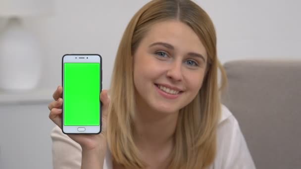 Красива дівчина, що показує смартфон із зеленим екраном, рекламний мобільний сайт — стокове відео
