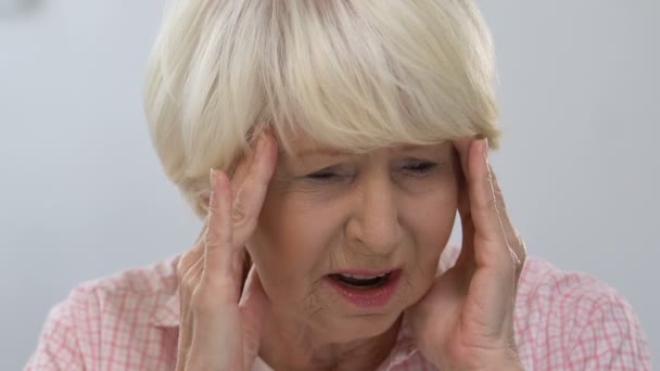 Старшая женщина массажный висок, страдает головной болью, расстройством здоровья — стоковое видео