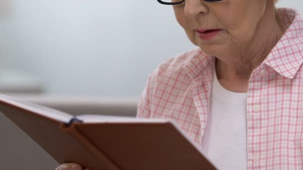 Alte Frau liest Buch, nimmt die Brille ab und leidet unter Sehstörungen — Stockvideo