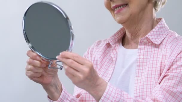 Smiling elderly woman looking in mirror, enjoying appearance, beauty care — Stock Video