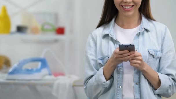 Sonriente ama de casa charlando en el teléfono inteligente, dejando hierro a bordo, riesgo de llama — Vídeos de Stock