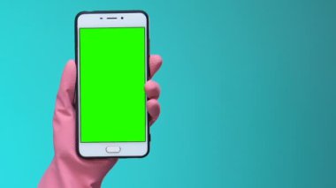 Kadın el eldiven yeşil ekran ile akıllı telefon gösteren, temizlik hizmeti