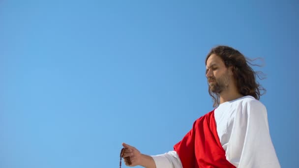 Jesus hält Rosenkranz gegen blau, gibt den Menschen Gebet, Hoffnung auf Erlösung — Stockvideo