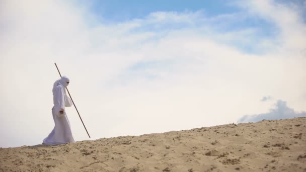 Арабська з персоналом ходьба в пустелі, збирається до мети, незважаючи на тепло і виснаження — стокове відео