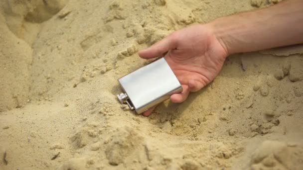 Mano con fiaschetta che cade senza vita sulla sabbia, effetti mortali della dipendenza da alcol — Video Stock