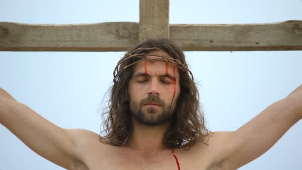 Yorgun İsa, insan günahlarını kefaret kamera bakarak, çapraz çivilenmiş — Stok video