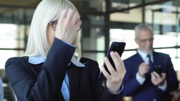 Emocionada empresaria mostrando sí gesto, leyendo grandes noticias por teléfono, éxito — Vídeo de stock