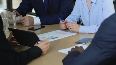 Şirket bütçesini, masa üzerindeki çizelgeleri, başarı stratejisini tartışan iş ortakları