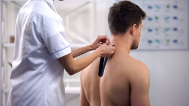 Hasta üst sırt üzerinde Y şeklinde bantlar uygulayan hekim, kas gerginliğini azaltır