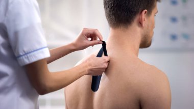 Hasta üst sırtında Y şekilli bantlar uygulayarak deneyimli Doktor, sağlık