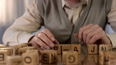 Erkek emekli ahşap küpler kelime yapmaya çalışıyor, yaşlılık demans, rehabilitasyon