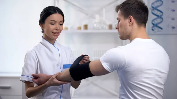 Erfaren Kvinnlig Ortopedi Tillämpa Armbåge Vadderad Ortosen Sportsman Patient — Stockfoto