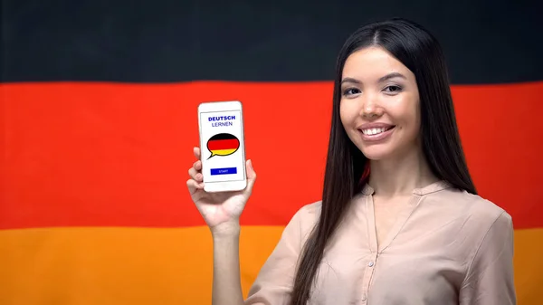 漂亮的女人拿着手机与语言学习应用程序 德国国旗的背景 — 图库照片