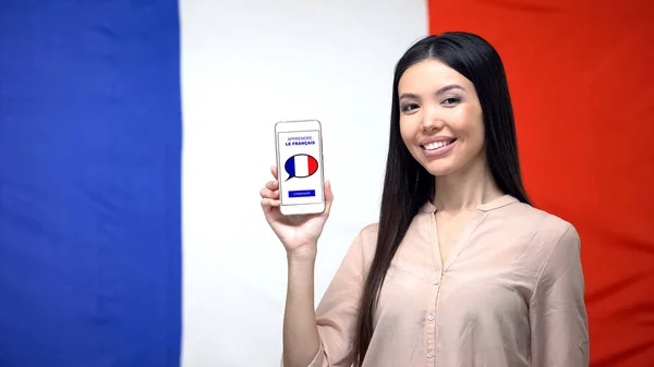 フランス国旗背景に対するスマートフォンを持つ女性 言語学習アプリ — ストック写真