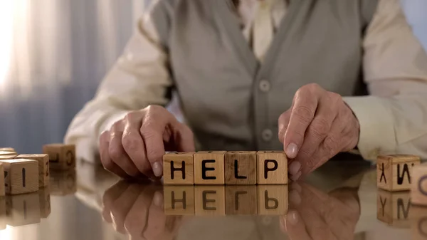 Ανώτερος Άνθρωπος Κάνοντας Λέξη Βοήθεια Από Ξύλινα Κύβους Στο Τραπέζι — Φωτογραφία Αρχείου